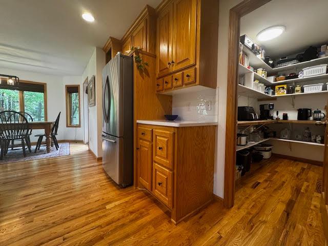 15224 Swallow St NW, Andover, MN 55304 - kitchen featuring freestanding refrigerator, brown cabinetry, wood finished floors, and light countertops