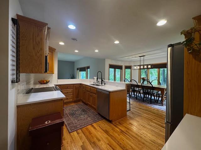 15224 Swallow St NW, Andover, MN 55304 - kitchen featuring stainless steel appliances, a sink, light wood-style floors, a peninsula, and brown cabinetry