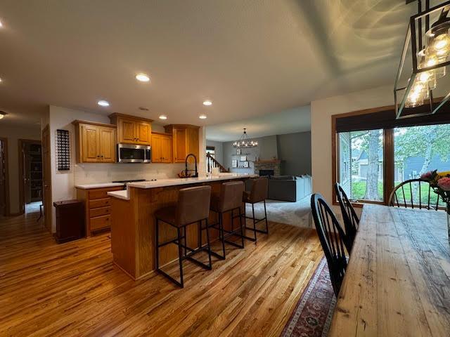 15224 Swallow St NW, Andover, MN 55304 - kitchen with stainless steel microwave, wood finished floors, a chandelier, open floor plan, and recessed lighting