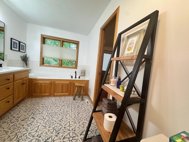 15224 Swallow St NW, Andover, MN 55304 - bathroom featuring decorative backsplash, a garden tub, vanity, and lofted ceiling