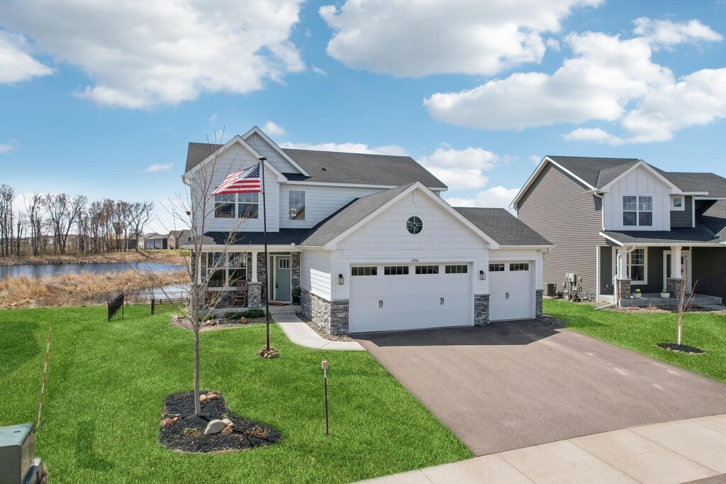 4356 128th Ln NE, Blaine, MN 55449 - craftsman inspired home featuring an attached garage, driveway, a front yard, and covered porch