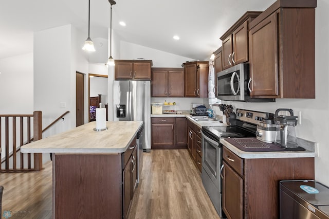 kitchen featuring stainless steel appliances, light wood-style floors, lofted ceiling, light countertops, and a kitchen island