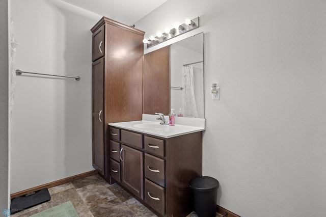 bathroom with vanity, baseboards, and stone finish floors