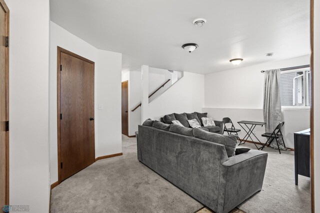 carpeted living area featuring stairway and baseboards