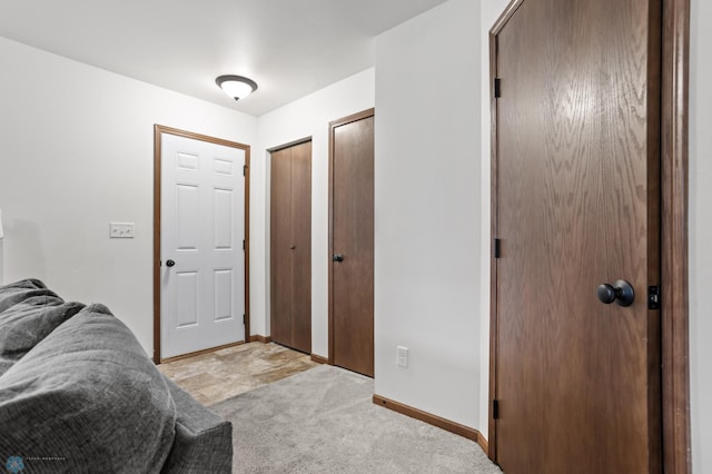 bedroom featuring two closets, baseboards, and light colored carpet