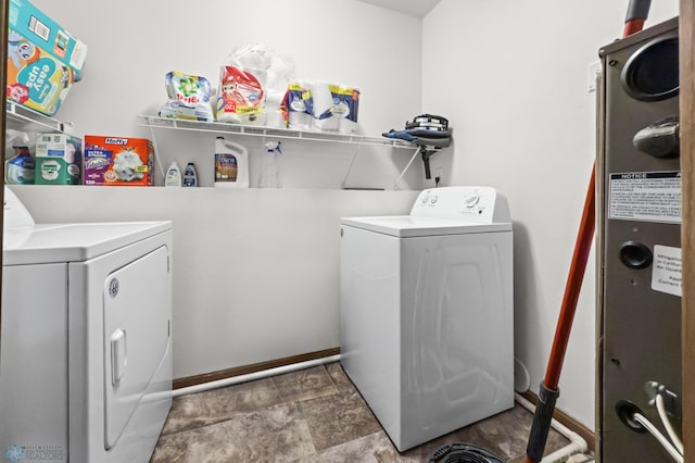 laundry room featuring washing machine and clothes dryer, baseboards, and stone finish flooring
