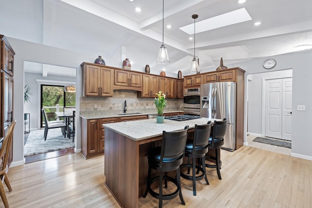 5401 Mount Normandale Dr, Bloomington, MN 55437 - kitchen featuring appliances with stainless steel finishes, a sink, a skylight, tasteful backsplash, and light stone countertops