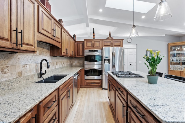 5401 Mount Normandale Dr, Bloomington, MN 55437 - kitchen with stainless steel appliances, a sink, a skylight, light stone countertops, and light wood-style floors