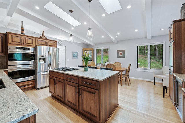 5401 Mount Normandale Dr, Bloomington, MN 55437 - kitchen with a skylight, stainless steel appliances, light wood-style floors, a kitchen island, and pendant lighting