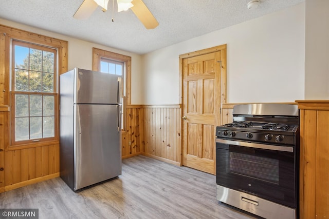 1134 Lincoln St NE, Minneapolis, MN 55413 - kitchen featuring appliances with stainless steel finishes, light wood-type flooring, wainscoting, a textured ceiling, and ceiling fan