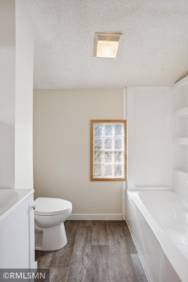 1134 Lincoln St NE, Minneapolis, MN 55413 - bathroom with toilet, wood finished floors, a textured ceiling, vanity, and baseboards