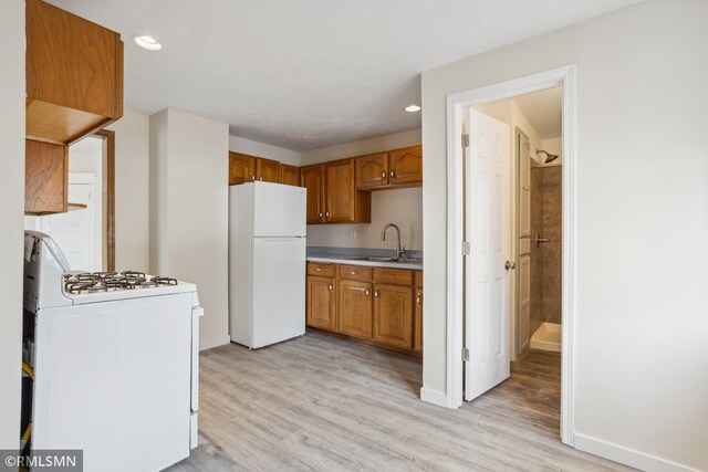 1134 Lincoln St NE, Minneapolis, MN 55413 - kitchen with white appliances, a sink, light countertops, light wood finished floors, and baseboards