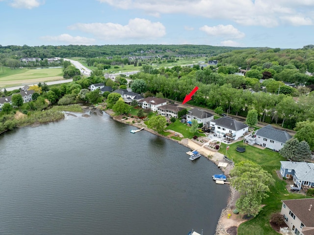 aerial perspective of suburban area featuring a large body of water and a tree filled landscape