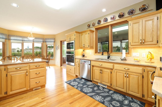 kitchen with appliances with stainless steel finishes, a sink, light wood-type flooring, decorative backsplash, and recessed lighting