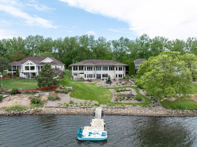 back of property with a water view, a yard, and view of scattered trees