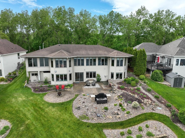 back of property featuring a fire pit, a patio, a yard, a shingled roof, and an attached garage