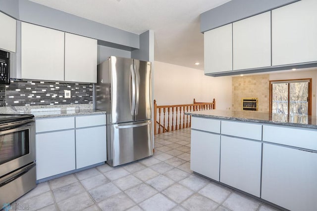 kitchen featuring appliances with stainless steel finishes, decorative backsplash, light stone counters, white cabinetry, and light tile patterned flooring