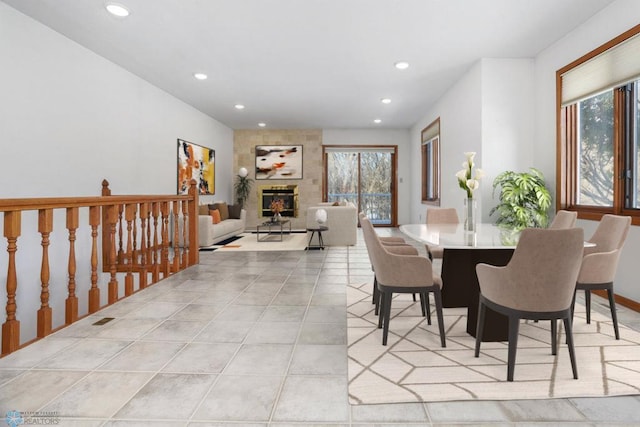 tiled dining space with recessed lighting and a large fireplace