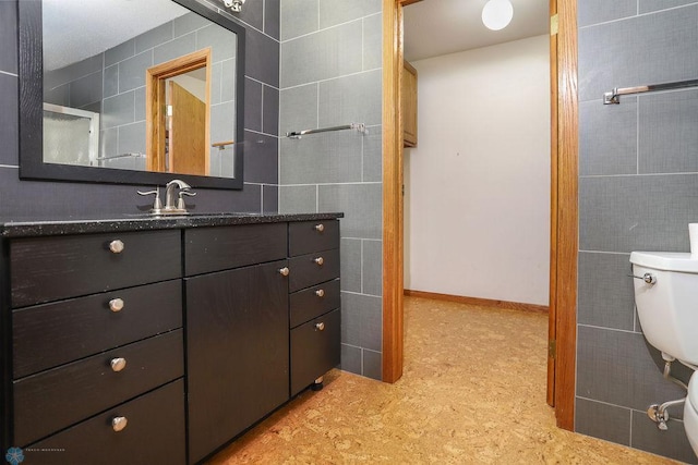 bathroom featuring vanity, tile walls, and toilet