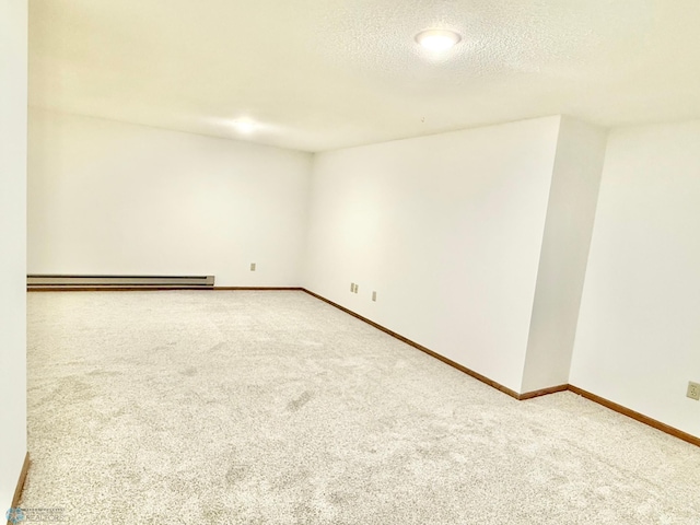 carpeted empty room with baseboard heating, a textured ceiling, and baseboards