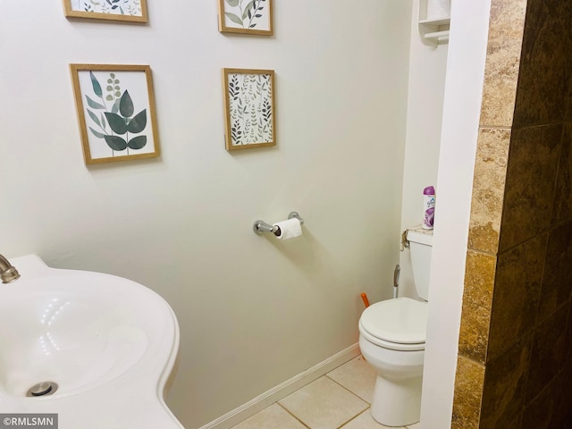 bathroom with a sink, tile patterned flooring, toilet, and baseboards