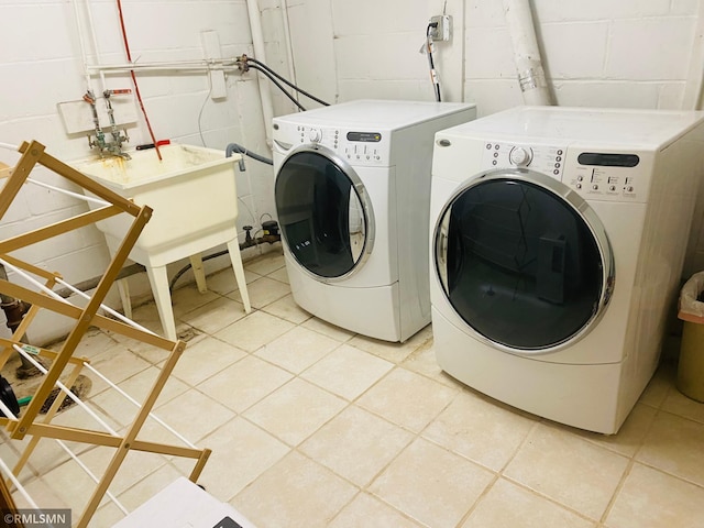 laundry room with washing machine and dryer, concrete block wall, and light tile patterned floors