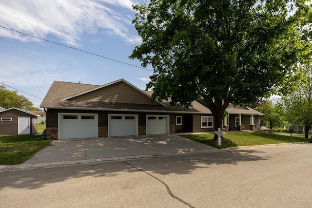 380 7th St SE, Chatfield, MN 55923 - view of front of house featuring a garage, concrete driveway, a front lawn, stone siding, and a storage unit