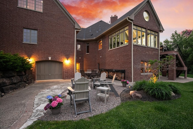130 Bergamot Dr, Medina, MN 55340 - rear view of house featuring driveway, brick siding, a garage, and a chimney