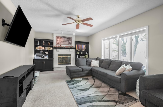 14994 Crane St NW, Andover, MN 55304 - carpeted living room with a textured ceiling, a ceiling fan, a fireplace, rail lighting, and built in shelves