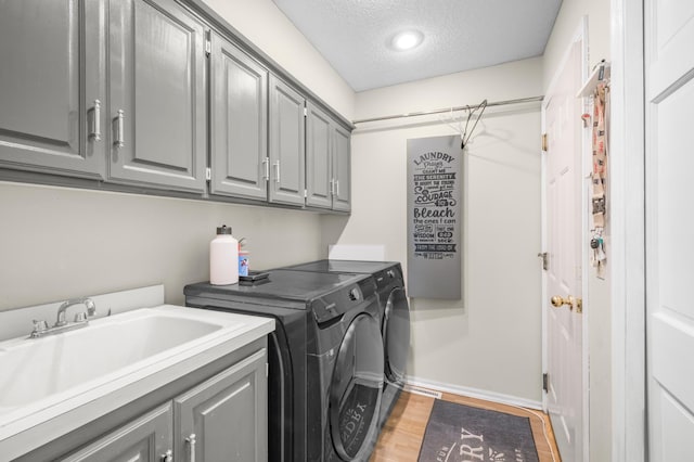 14994 Crane St NW, Andover, MN 55304 - laundry room featuring washer and dryer, cabinet space, a textured ceiling, and light wood-style flooring