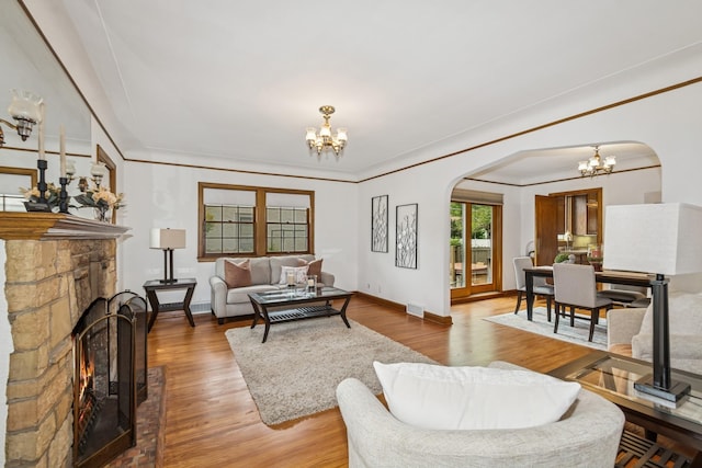 4207 Vincent Ave, Minneapolis, MN 55412 - living room with arched walkways, a chandelier, a lit fireplace, wood finished floors, and crown molding