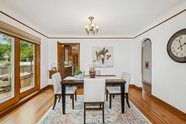 4207 Vincent Ave, Minneapolis, MN 55412 - dining room with a chandelier, arched walkways, light wood-type flooring, and crown molding