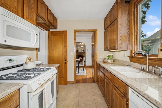 4207 Vincent Ave, Minneapolis, MN 55412 - kitchen featuring white appliances, light tile patterned floors, brown cabinets, and light stone counters