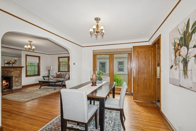 4207 Vincent Ave, Minneapolis, MN 55412 - dining space featuring a chandelier, arched walkways, light wood finished floors, and a fireplace