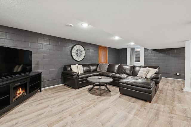 621 Irving Ave NW, Elk River, MN 55330 - living area featuring a warm lit fireplace, wood finished floors, and concrete block wall