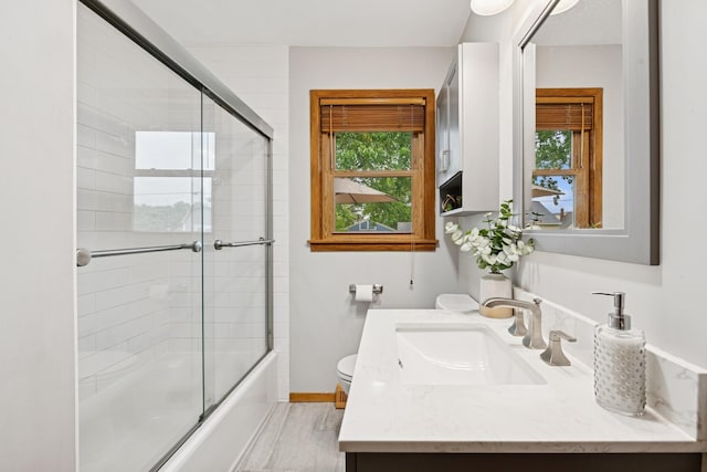 621 Irving Ave NW, Elk River, MN 55330 - bathroom featuring healthy amount of natural light, vanity, bath / shower combo with glass door, and toilet