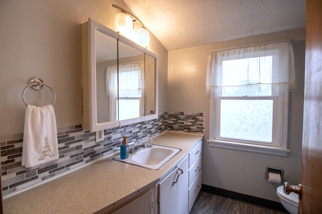 bathroom with a textured ceiling, toilet, backsplash, vanity, and lofted ceiling