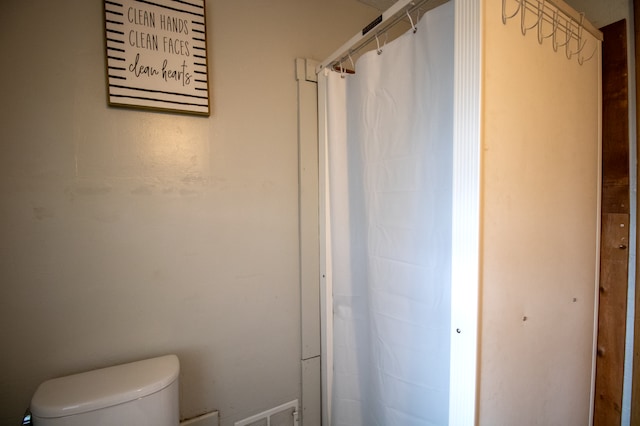 full bathroom with toilet and a shower with shower curtain