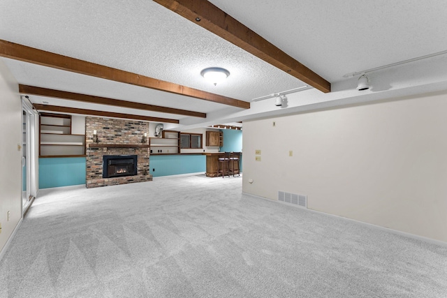 18520 29th Ave N, Plymouth, MN 55447 - unfurnished living room with carpet, beamed ceiling, a textured ceiling, bar area, and rail lighting