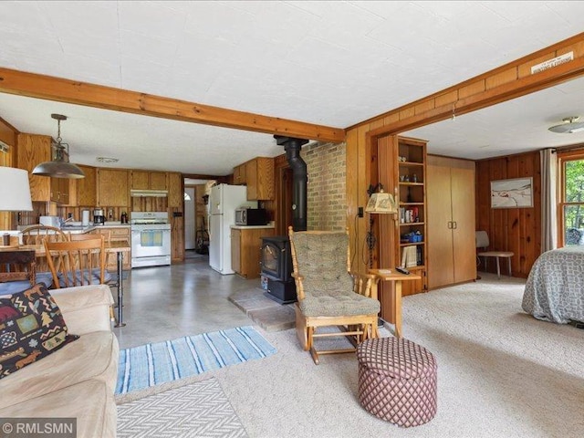 1403 County 5 NW, Hackensack, MN 56452 - living area featuring wooden walls, a wood stove, beamed ceiling, and concrete flooring