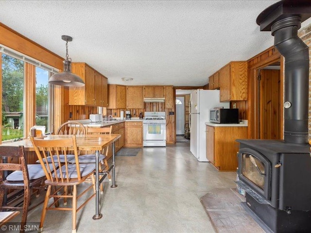 1403 County 5 NW, Hackensack, MN 56452 - kitchen with white gas range, stainless steel microwave, a wood stove, under cabinet range hood, and light countertops