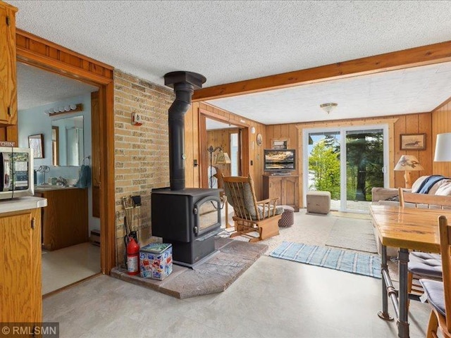 1403 County 5 NW, Hackensack, MN 56452 - living room featuring a wood stove, wooden walls, a textured ceiling, and beamed ceiling