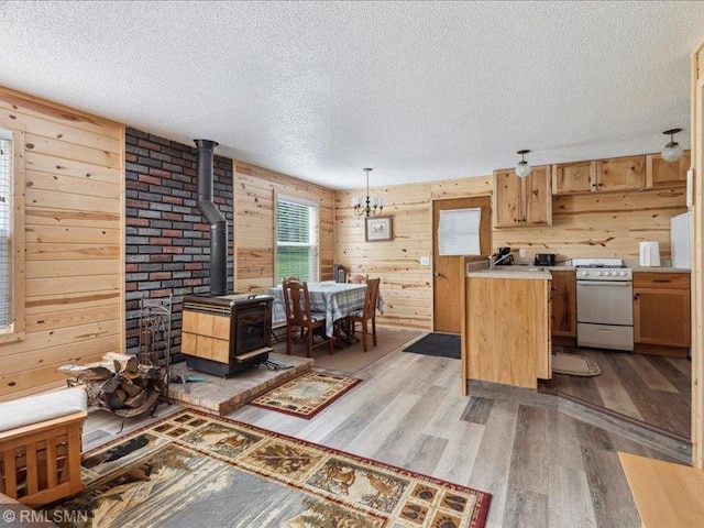 1403 County 5 NW, Hackensack, MN 56452 - kitchen featuring white gas range, a textured ceiling, light wood-type flooring, a wood stove, and wood walls