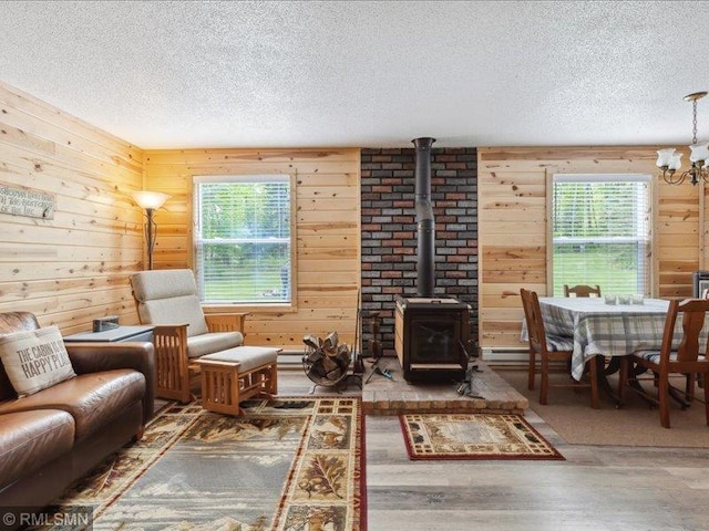 1403 County 5 NW, Hackensack, MN 56452 - living room with a textured ceiling, wood finished floors, a wood stove, a chandelier, and wood walls