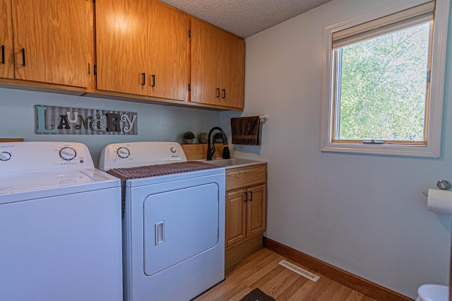 114 Iowa Ave, Hoffman, MN 56339 - washroom with washing machine and clothes dryer, light wood-style floors, baseboards, cabinet space, and a textured ceiling