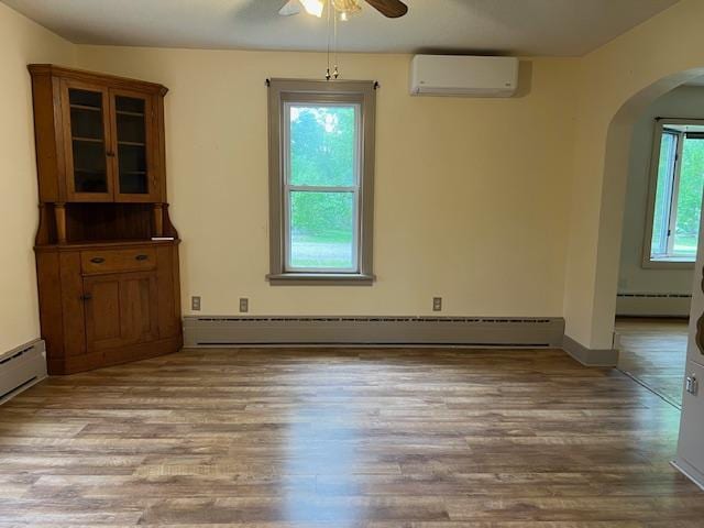 323 Weisel St, Litchfield, MN 55355 - unfurnished dining area featuring a wall mounted air conditioner, arched walkways, a ceiling fan, and baseboard heating