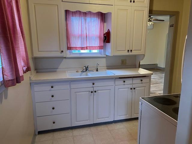 323 Weisel St, Litchfield, MN 55355 - kitchen with white electric range, a sink, white cabinetry, and a baseboard radiator