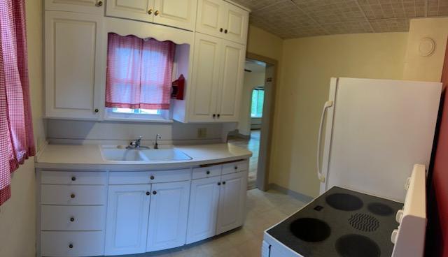 323 Weisel St, Litchfield, MN 55355 - kitchen with freestanding refrigerator, range with electric stovetop, white cabinetry, a sink, and plenty of natural light