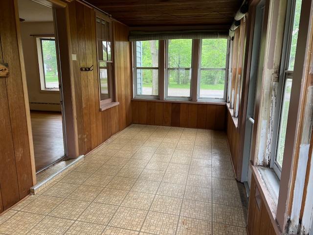 323 Weisel St, Litchfield, MN 55355 - unfurnished sunroom featuring a baseboard heating unit, wooden walls, wooden ceiling, and tile patterned floors