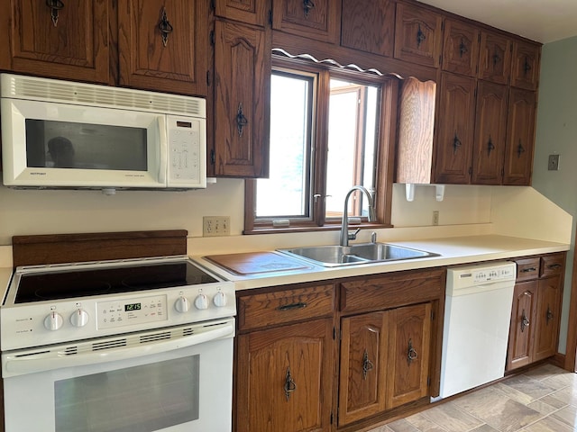 kitchen featuring white appliances, a sink, and light countertops